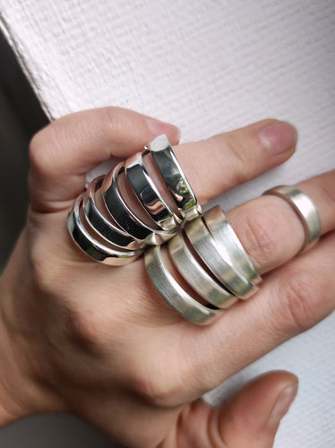 A woman's hand holding a pair of Kathrin Jona Stacker rings - Wide band.