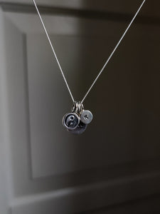 A Kathrin Jona silver necklace with two 'INITIAL' silver letter charms hanging from it, attached to a matching chain.