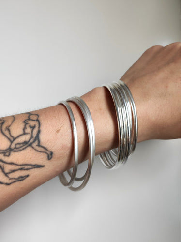 A woman with a tattoo on her arm wearing Kathrin Jona's hand forged Round Silver Bangles.