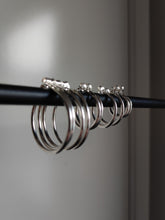 Load image into Gallery viewer, Four Kathrin Jona silver hoop earrings of different sizes hanging on a black rod.
