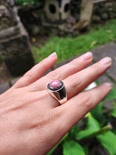 Load image into Gallery viewer, A woman&#39;s hand holding a Rhodochrosite Silver Signet Ring by Kathrin Jona with a pink stone.
