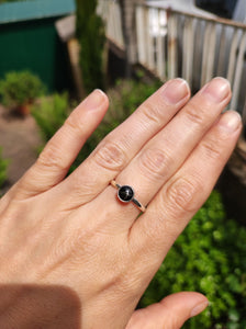 A woman's hand holding a Round Obsidian Silver Stacker Ring by Kathrin Jona.