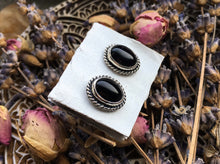 Load image into Gallery viewer, A pair of Kathrin Jona Onyx Stud Earrings No.2 on top of a box.
