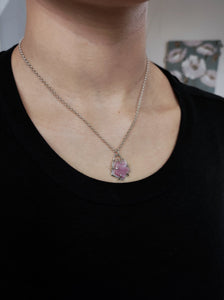 A woman wearing a Pentagon Mother of Pearl Necklace by Kathrin Jona with a pink stone.