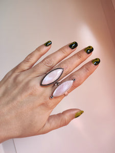 A hand holding a Mother of Pearl Ring adjustable with a pink stone on it from Kathrin Jona.