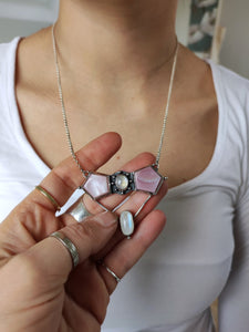 A woman holding up a Kathrin Jona Mother of Pearl Statement Necklace with a pink stone.