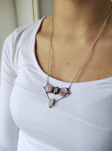 A woman wearing a Mother of Pearl Statement Necklace by Kathrin Jona with a pink stone.
