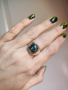 A woman wearing a Kathrin Jona Leopard Opal 9k Gold Signet Ring with a green and black stone.