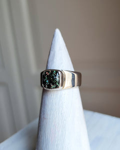 A Leopard Opal Silver Ring S by Kathrin Jona with a black druzy stone on top of a pedestal.