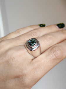 A woman's hand holding a Leopard Opal Silver Signet Ring S by Kathrin Jona with a green stone.