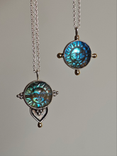 Load image into Gallery viewer, Two necklaces from Kathrin Jona, called the Fair Labradorite Sun Face Necklace, feature pendants with sun-themed designs and blue and green iridescent faces made from labradorite. The chains are crafted from recycled silver, and the pendants include metallic accents.
