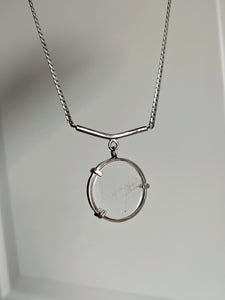 The Clear Quartz Moto Necklace by Kathrin Jona showcases a transparent pendant set in a minimalist metal frame, elegantly suspended from an upcycled silver chain.