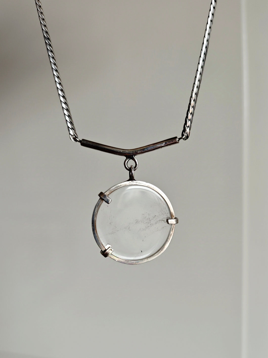 The Clear Quartz Moto Necklace by Kathrin Jona features a clear circular pendant on a recycled silver chain, showcasing a minimalist design against a neutral background.