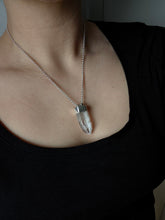 Load image into Gallery viewer, A person wears a black top, accessorized with the Australian Clear Quartz Necklace #2 by Kathrin Jona, an adjustable silver chain necklace crafted from recycled silver and featuring a clear quartz pendant.
