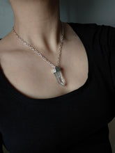 Load image into Gallery viewer, A person is adorned with a Kathrin Jona Australian Clear Quartz Necklace #1, featuring a silver chain and a large, clear quartz pendant.
