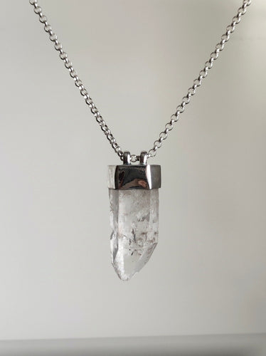 The Australian Clear Quartz Necklace #2 by Kathrin Jona showcases a clear Quartz crystal pendant on a silver chain, elegantly crafted from recycled silver and displayed against a plain background.