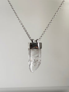 The Australian Clear Quartz Necklace #2 by Kathrin Jona showcases a clear Quartz crystal pendant on a silver chain, elegantly crafted from recycled silver and displayed against a plain background.