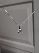 Load image into Gallery viewer, A Kathrin Jona sterling silver necklace, adorned with a &#39;SUN&#39; charm, hangs from a door.

