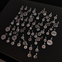 Load image into Gallery viewer, A group of &#39;SUN&#39; silver charms by Kathrin Jona arranged on a table.
