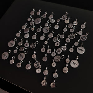 A group of 'SUN' silver charms by Kathrin Jona arranged on a table.
