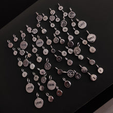 Load image into Gallery viewer, A group of &#39;SUN&#39; silver charms arranged on a table by Kathrin Jona.
