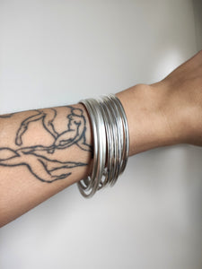 A woman wearing Round Silver Bangles hand forged from 925 sterling silver, with tattoos on her arm.