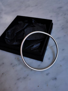 Hand forged Kathrin Jona round silver bangle in a black box.