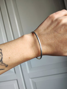 A woman wearing a Round Silver Bangle by Kathrin Jona with a tattoo on it.