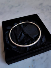 Load image into Gallery viewer, A hand forged, Kathrin Jona round silver bangle with a matt finish presented in a black box.
