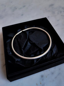 A hand forged, Kathrin Jona round silver bangle with a matt finish presented in a black box.