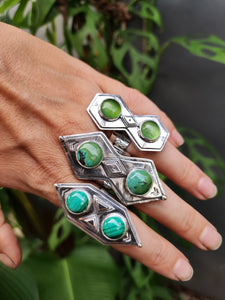 A woman's hand holding a Kathrin Jona Green Shield Jadeite Ring #2 with green stones.