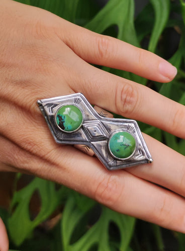 A woman's hand is holding a Kathrin Jona Green Shield Turquoise Ring #1.