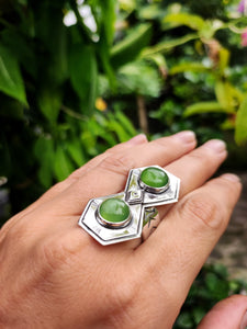 A hand holding a Green Shield Jadeite Ring #2 with two green jade stones from Kathrin Jona.