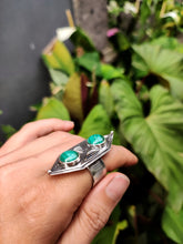 Load image into Gallery viewer, A hand holding a Green Shield Malachite Ring #3 by Kathrin Jona in front of plants.
