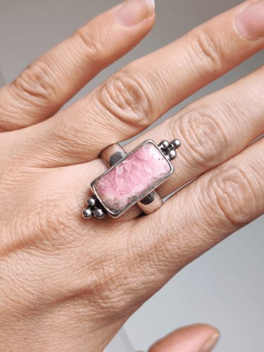 A woman's hand holding a Rhodochrosite Statement Ring by Kathrin Jona.