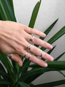 A woman's hand holding a pair of Kathrin Jona Stacker rings with rounded edges.