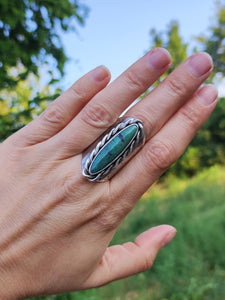 A hand holding a Turquoise Shield Ring from the brand Kathrin Jona with a turquoise stone.