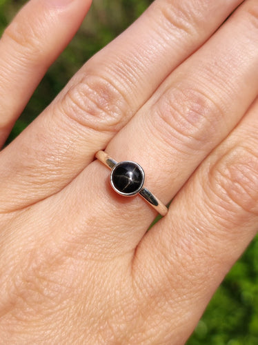A woman's hand holding a Round Obsidan Silver Stacker Ring by Kathrin Jona.