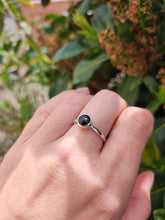 Load image into Gallery viewer, A hand holding a Round Obsidan Silver Stacker Ring with a black sapphire stone by Kathrin Jona.
