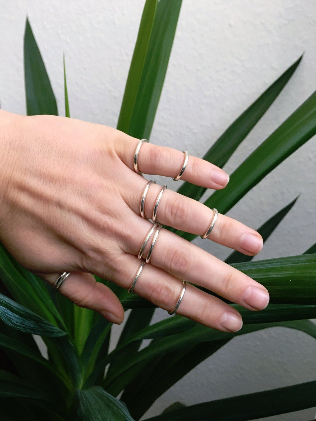 A woman's hand with several Kathrin Jona Stacker rings - round on it.