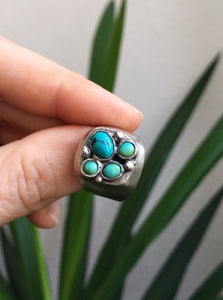 A person holding a Turquoise Cluster Signet Ring by Kathrin Jona.