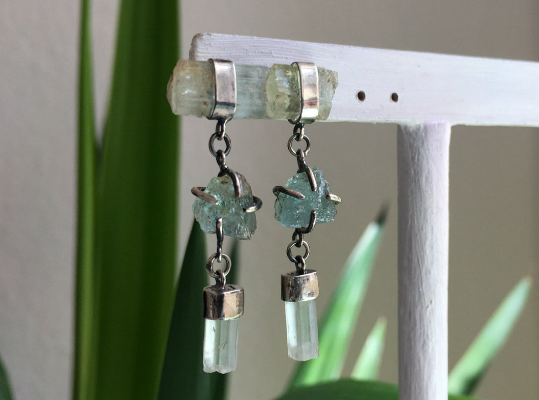 A pair of Three of Aquamarine Earrings by Kathrin Jona with aquamarine crystals hanging from them.