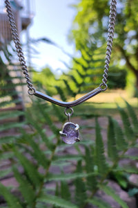 An Amethyst Moto Bar Necklace from Kathrin Jona brand hangs from a silver chain.
