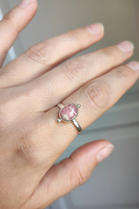 A woman's hand holding a Rhodochrosite Stacker Ring by Kathrin Jona.