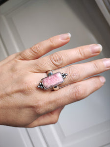 A woman's hand holding a Rhodochrosite Statement Ring by Kathrin Jona.